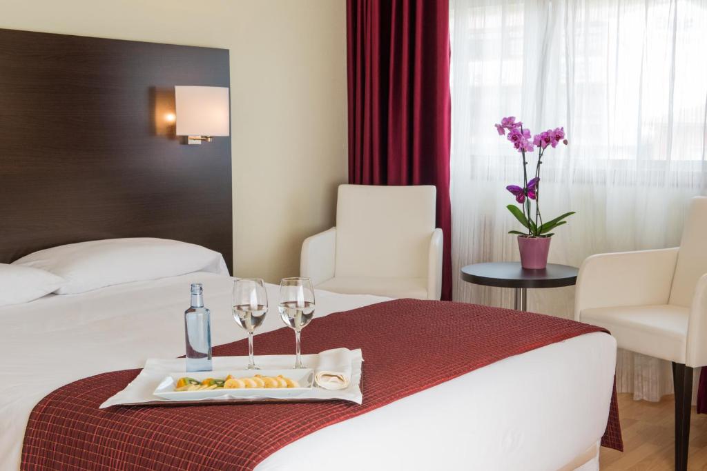 圣地亚哥－德孔波斯特拉圣地亚哥阿波斯托尔酒店的酒店客房,配有一张带食品和酒杯托盘的床