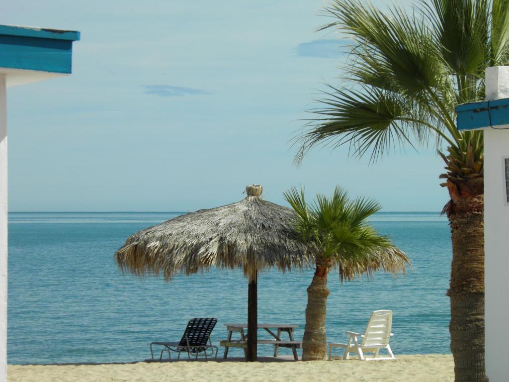 圣费利佩#52 Bungalow Seaside Hotel & Victors RV Park的海滩上设有椅子和草伞,棕榈树