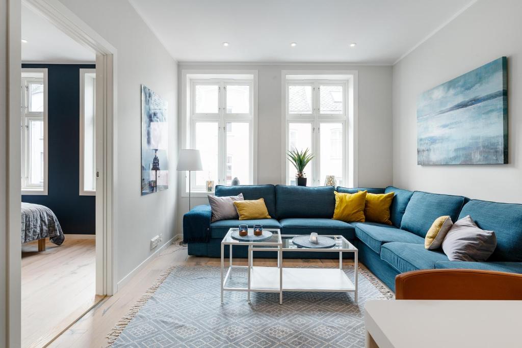 卑尔根Høyden Apartments的客厅配有蓝色的沙发和黄色的枕头。