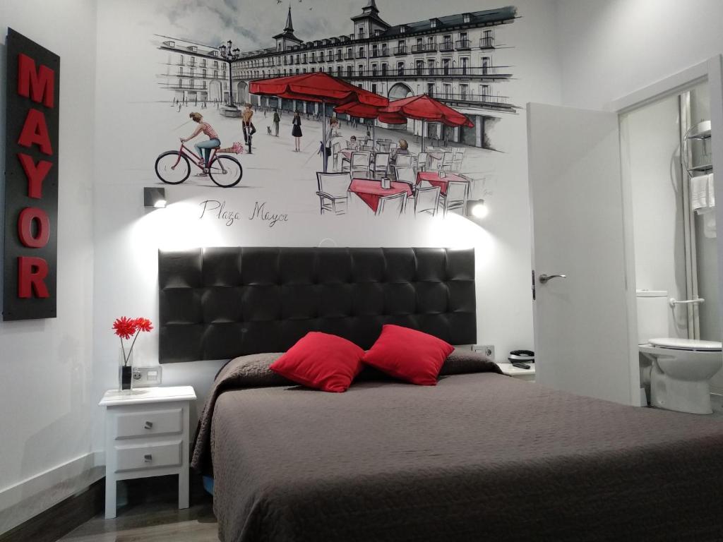 马德里劳里亚旅馆的卧室配有一张带红色枕头的床,墙上挂着一张海报