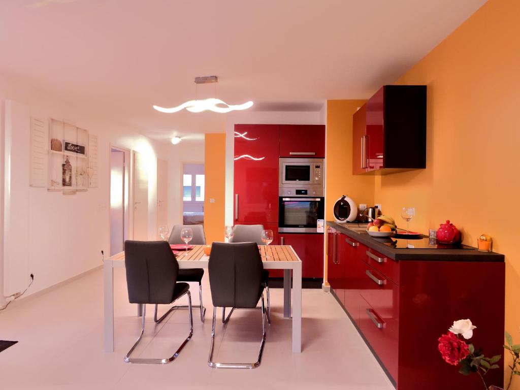 安锡LE LYRIQUE的厨房配有红色橱柜和桌椅