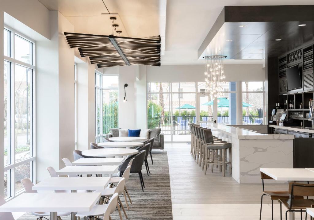 德斯坦Hyatt Place Sandestin at Grand Blvd的有白色桌椅和窗户的餐厅