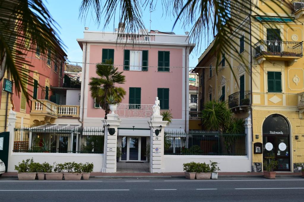 瓦拉泽丽多酒店的棕榈树城市街道上的粉红色建筑