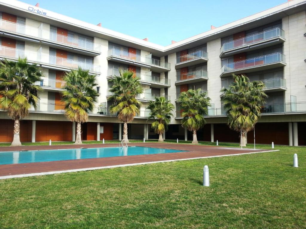坎布里尔斯Apartamento Playa Esquirol的公寓大楼设有游泳池和棕榈树