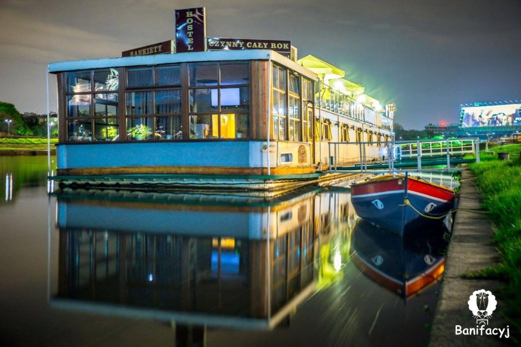 克拉科夫The Boat - Hostel&Chill的河上一座建筑物,水中有一船