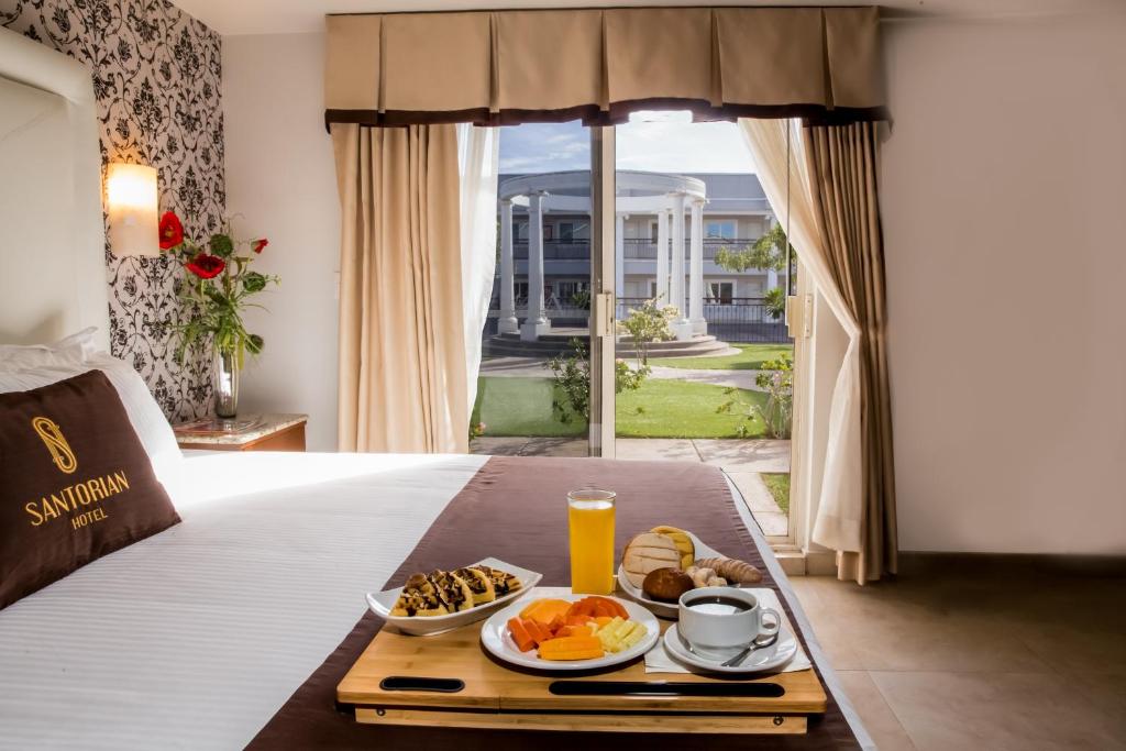 埃莫西约Hotel Santorian的在酒店客房内的床上的早餐托盘