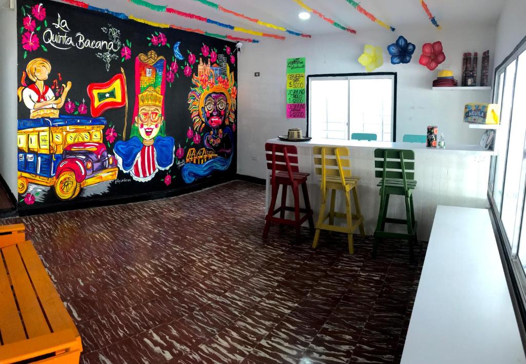 巴兰基亚La Quinta Bacana的一间房间,墙上有画作,设有酒吧