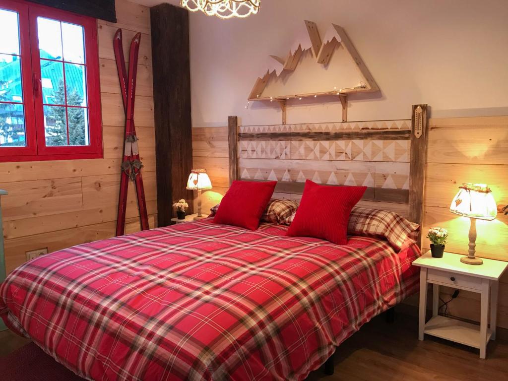 坎丹奇奥Apartamentos LÓRIEN Candanchú的一间卧室配有红色的床和两个红色枕头