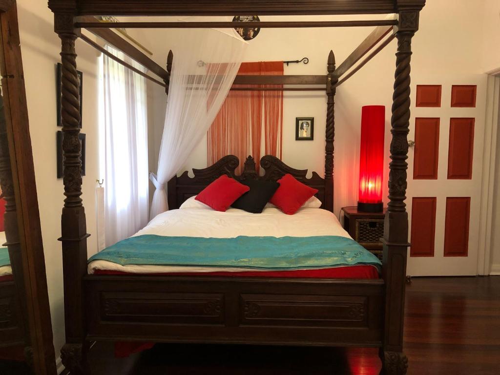 飞鱼湾Island Time Guest Room的一间卧室配有一张带红色枕头的天蓬床
