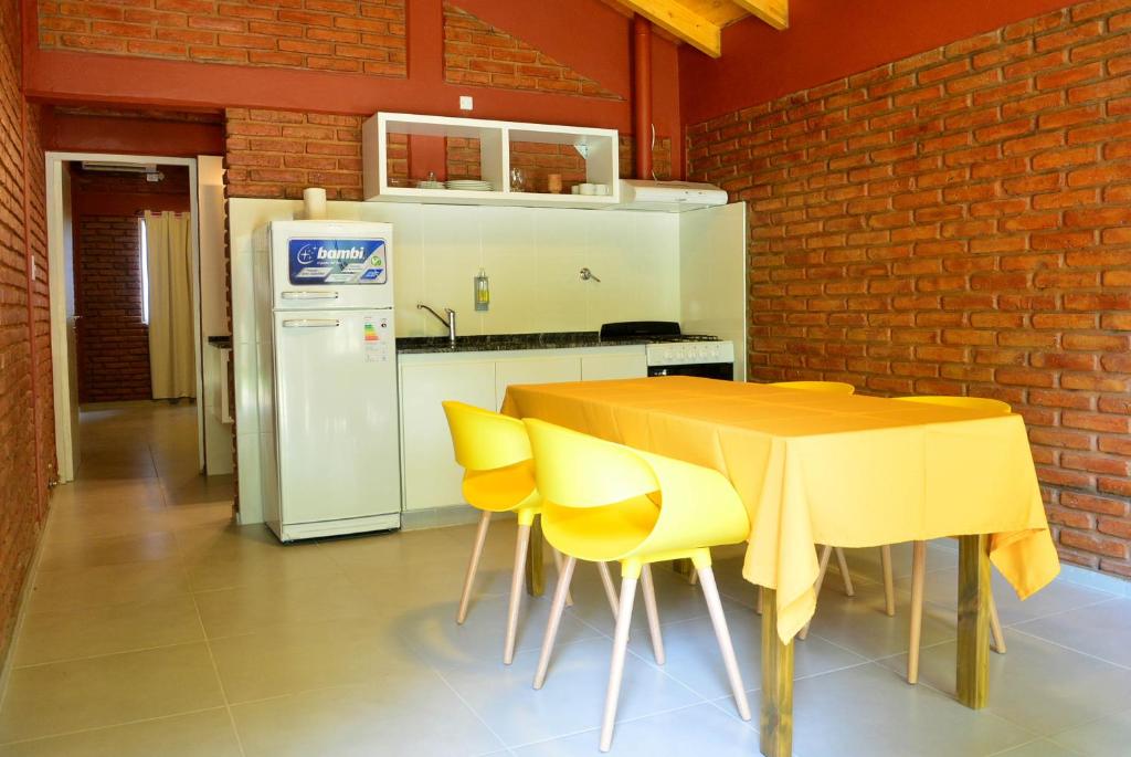圣拉斐尔Cabañas Las Marias的厨房配有桌子、黄色椅子和冰箱