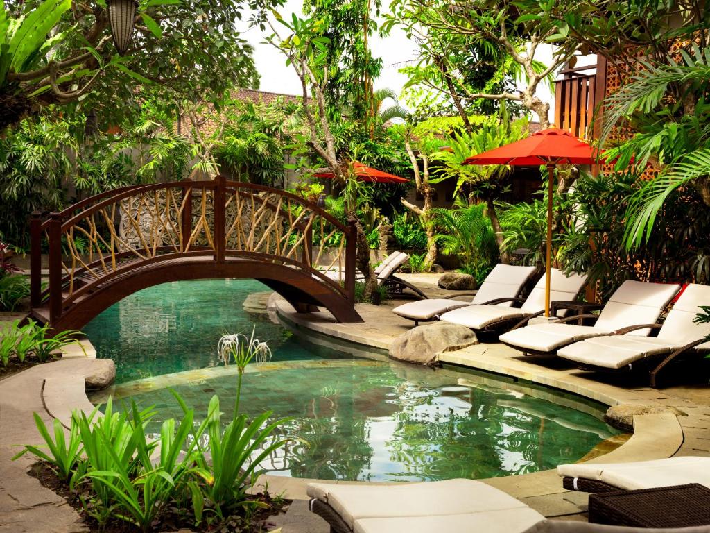 乌布Adiwana Monkey Forest的花园中一座带躺椅的游泳池桥