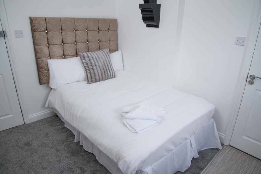 贝肯翰姆TLK Apartments & Hotel - Beckenham的一张带白色床单的床和一张位于客房内的床头板