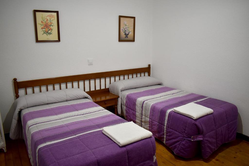 莱昂HOSTAL OVIEDO的紫色床单的客房内的两张床