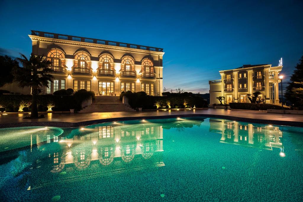 地拉那Royal Hill Hotel的一座大型建筑,晚上设有游泳池