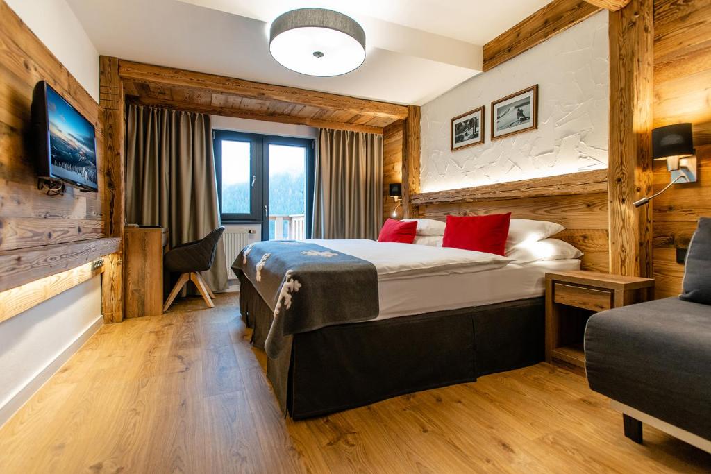 什平德莱鲁夫姆林奥林匹亚酒店的配有红色枕头的床的酒店客房