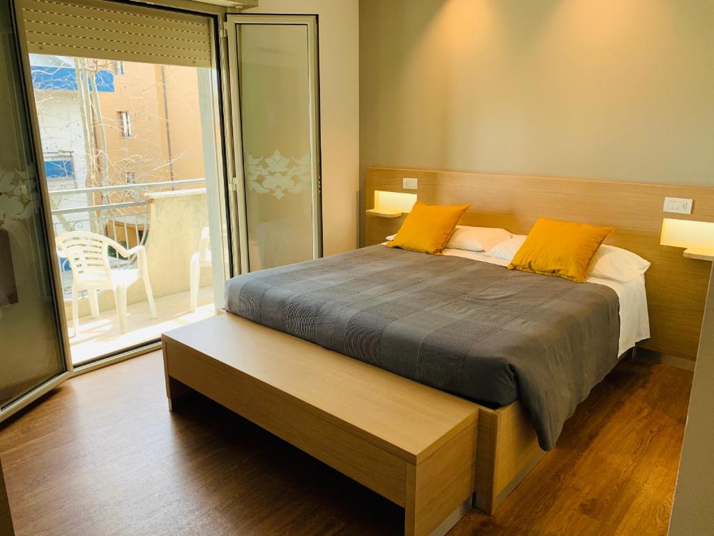 里乔内Hotel Liane Riccione的一间卧室配有一张带黄色枕头的床和一个阳台