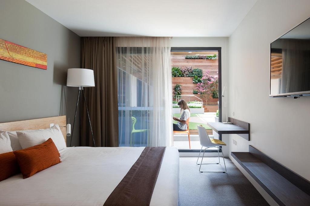 墨尔本Jasper Boutique Hotel的一间卧室配有一张床、一张书桌和一个窗户。