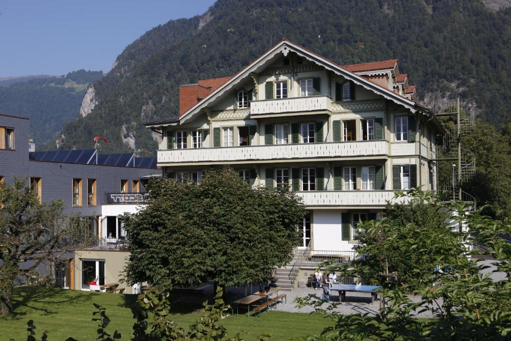 因特拉肯Chalet Hostel @ Backpackers Villa Interlaken的一座白色的大建筑,在山前有楼梯