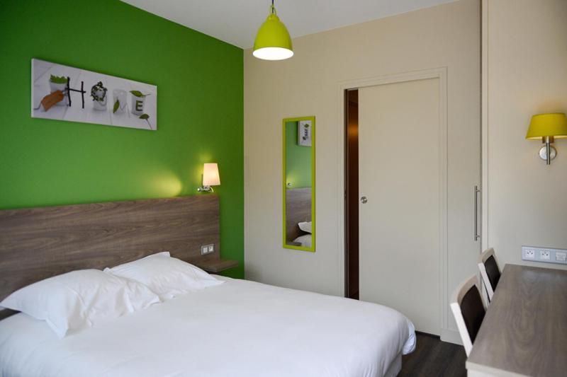 拉勒塞勒罗吉斯林提勒尔酒店（科特迪瓦PARC餐厅）的绿色卧室配有白色的床和一张桌子