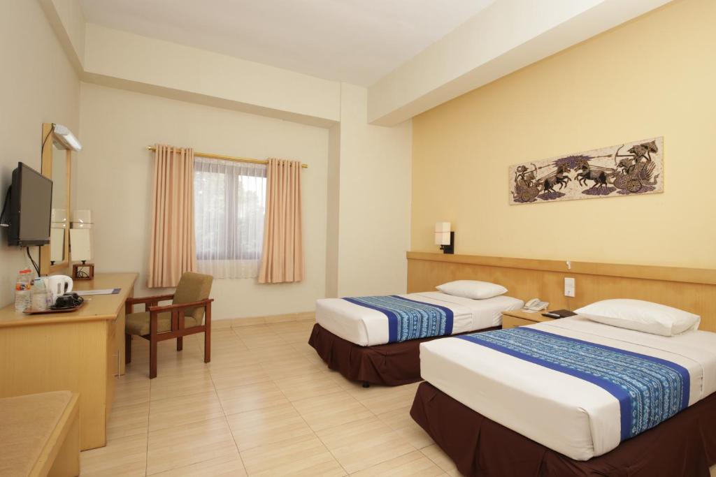 日惹University Club (UC) Hotel UGM的酒店客房配有两张床和一张书桌