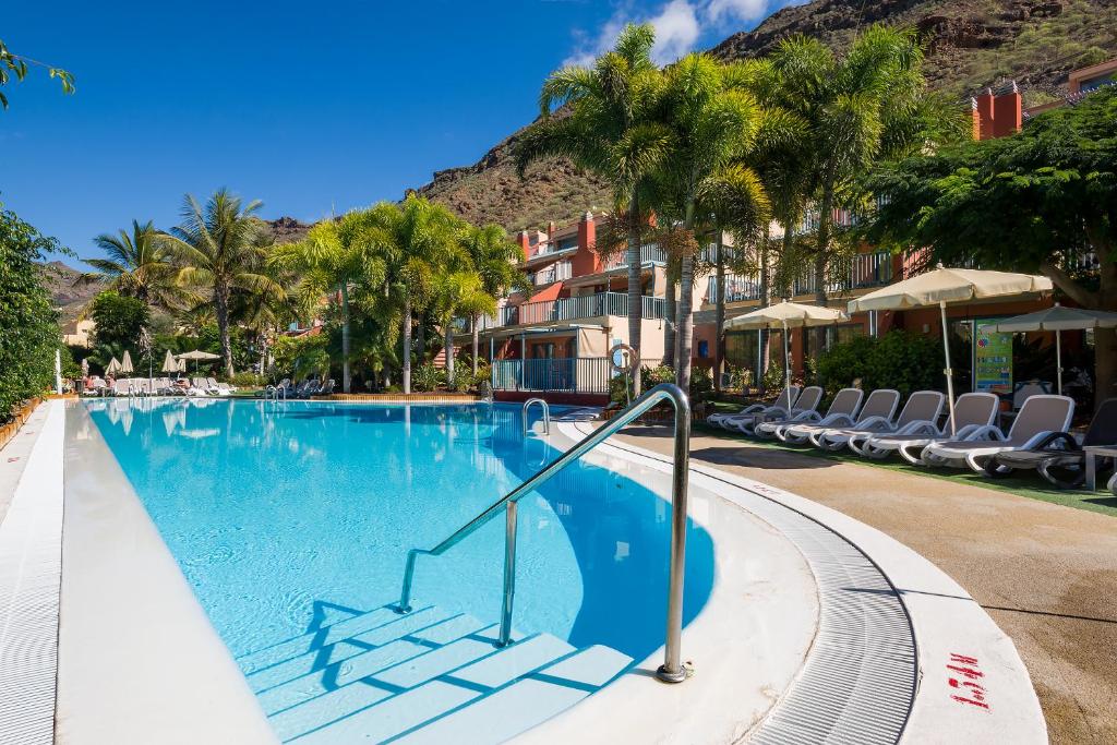 莫甘海滩莫干山谷温馨公寓的一座带椅子和树木的度假村游泳池