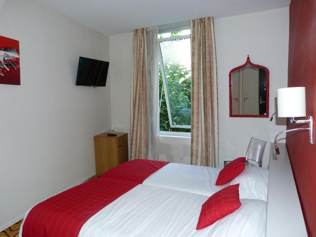 昂古莱姆Cit'Hotel Europeen的一间卧室配有一张带红色枕头的床和一扇窗户