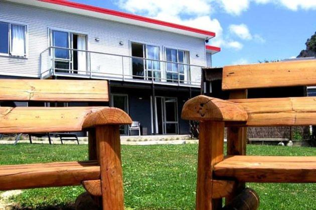 皮克顿Tombstone Motel, Lodge & Backpackers的坐在大楼前的木凳