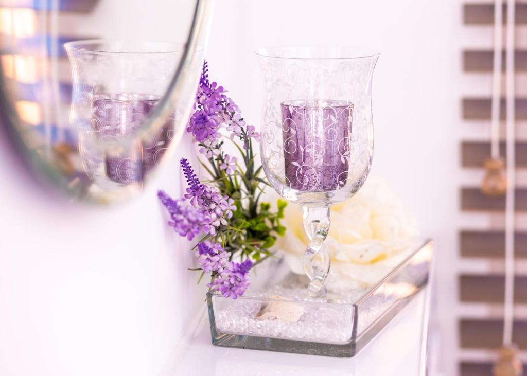 德米茨Boutique Hotel ma maison的桌子上放两杯酒和紫色花