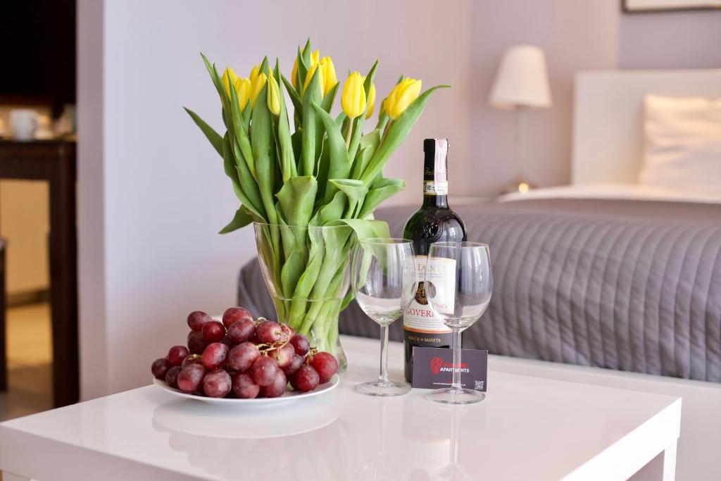 克拉科夫Kraków Apartments - Friedleina Studio Apartments的一张桌子,上面放着一瓶葡萄酒和一碗水果