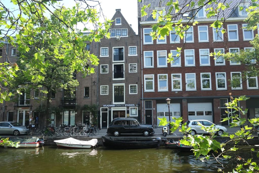 阿姆斯特丹B＆B弗拉基米尔影城酒店的一条运河,在建筑前停有船只和汽车
