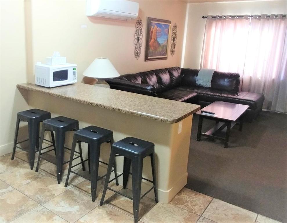 佩吉Lake Powell Motel &amp; Apartments的客厅设有带凳子和沙发的酒吧