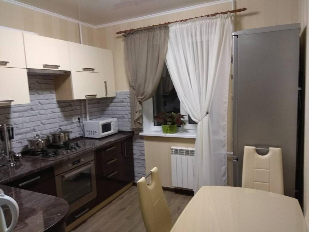 尼科波尔вулиця Електрометалургів的厨房配有白色橱柜和桌椅