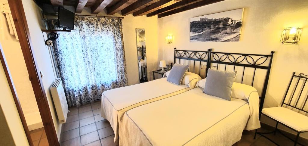 托莱多拉坡萨达得可多维旅馆的一间卧室设有两张床、一把椅子和一个窗户。
