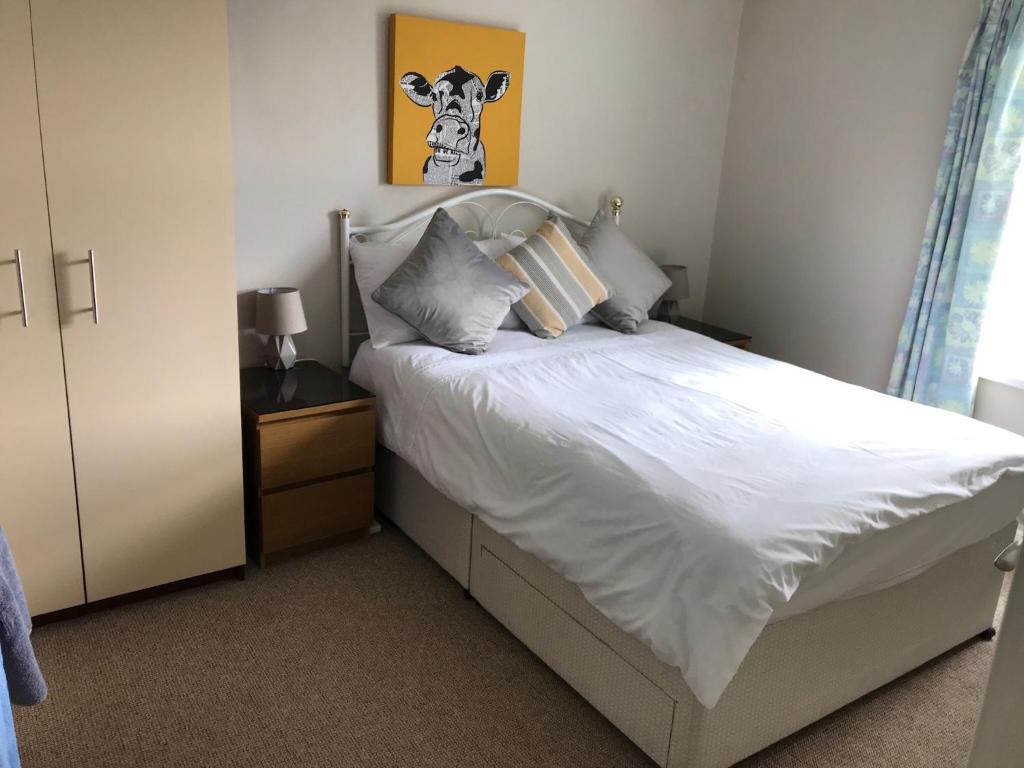斯图尔特港Portstewart Holiday Home的卧室配有白色床,墙上挂着牛的照片