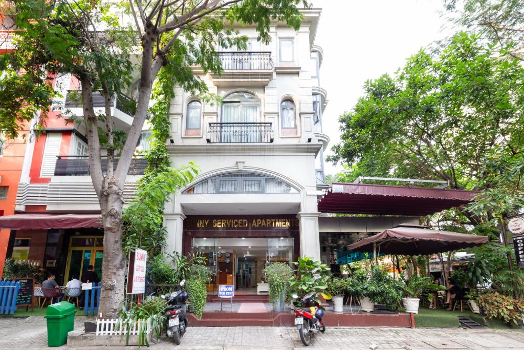 胡志明市阳光酒店和公寓的前面有棵树的白色建筑