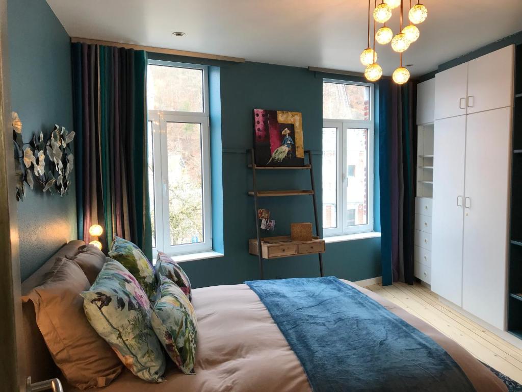 斯帕Lola des Sources的一间卧室拥有蓝色的墙壁,配有一张带枕头的床。
