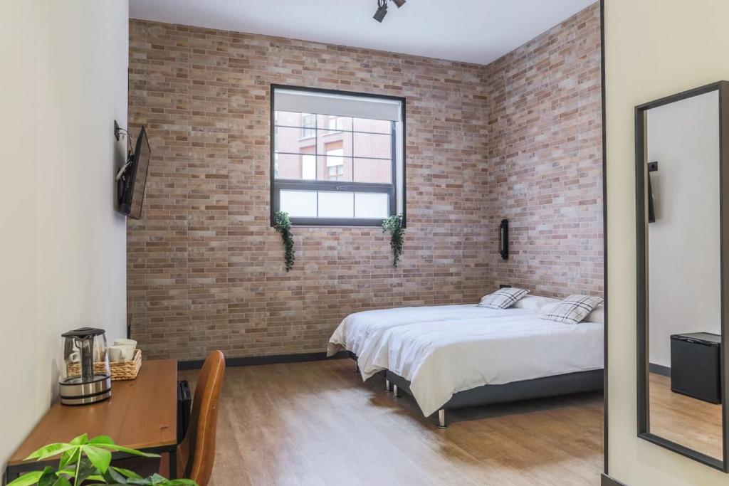毕尔巴鄂Pensión H30 Bilbao的卧室设有砖墙、一张床和一张桌子