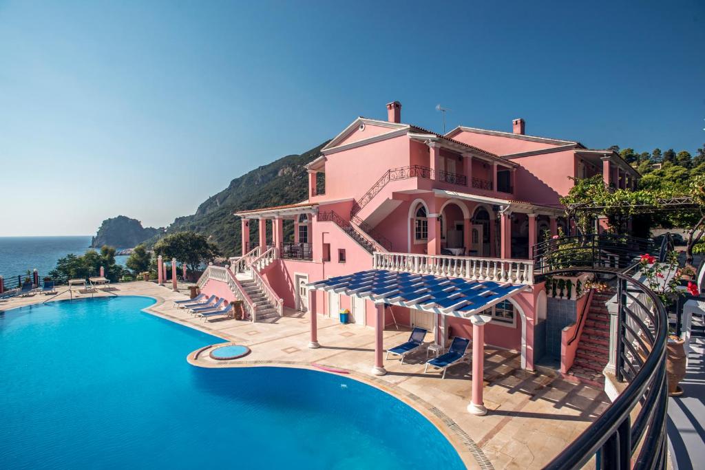 埃尔莫奈斯Hotel Elena Ermones的粉红色的房子,在海边设有一个游泳池