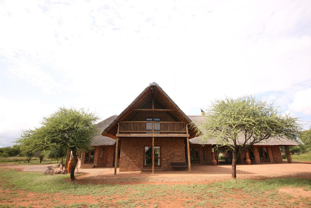 贝拉贝拉Makhato Bush Lodge 109的茅草屋顶和两棵树的房子