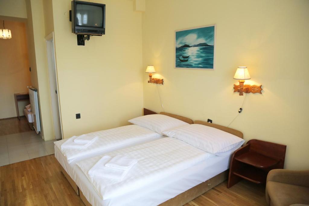 布达佩斯Hotel Bara Junior的卧室配有白色的床和电视。