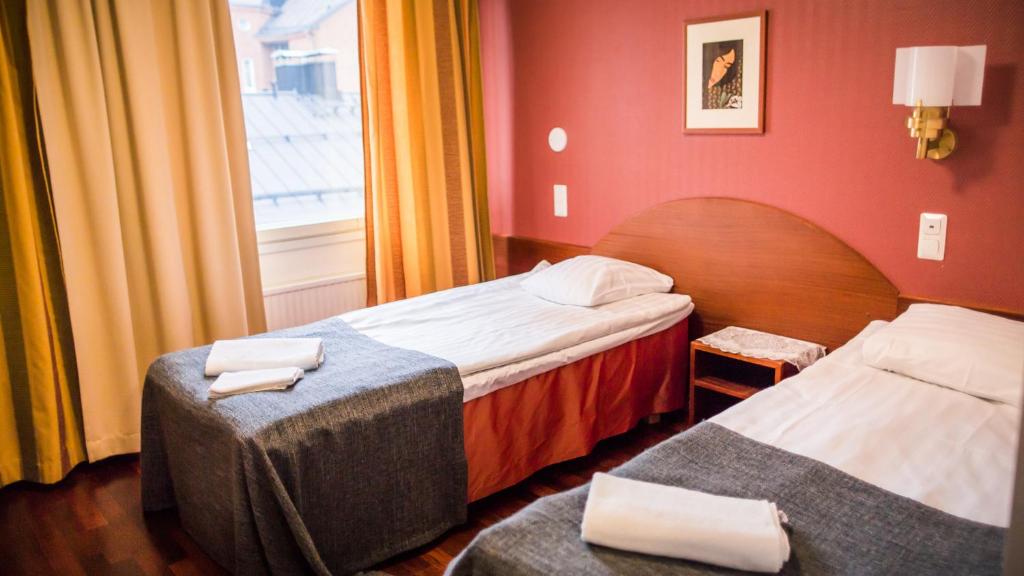 坦佩雷Kesähotelli Aurora的酒店客房设有两张床和窗户。