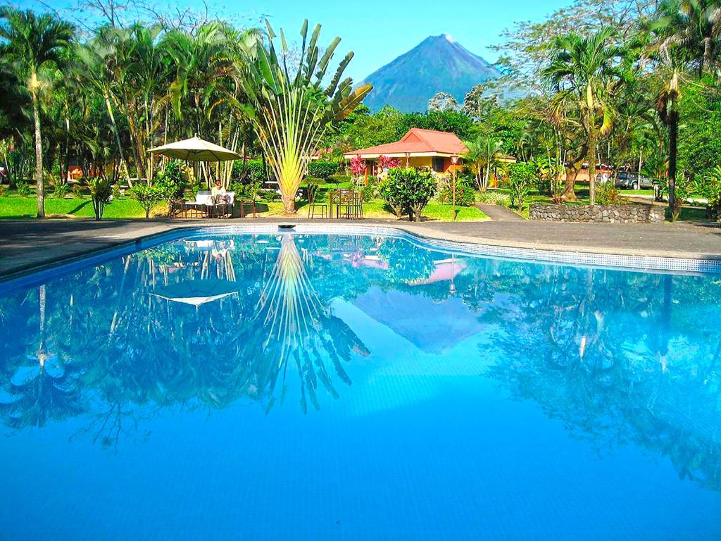 福尔图纳阿雷纳尔乡村酒店的一座蓝色的游泳池,后面是一座山
