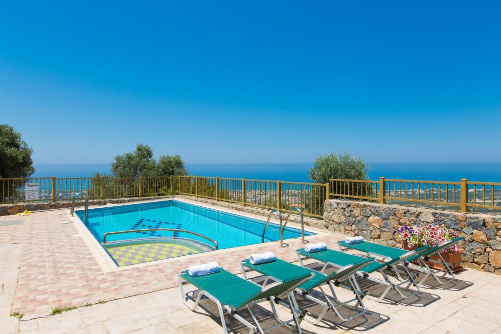 马鲁拉斯Maroulas Villas Ioanna & Stavros, stunning views, By ThinkVilla的一个带桌椅的游泳池,以及背景海洋
