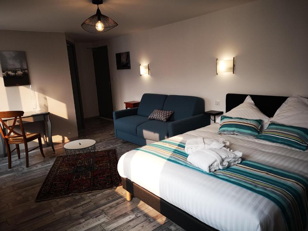 UrepelHôtel/Restaurant C'Vall的一间卧室配有一张床和一张蓝色的沙发,另一间卧室配有