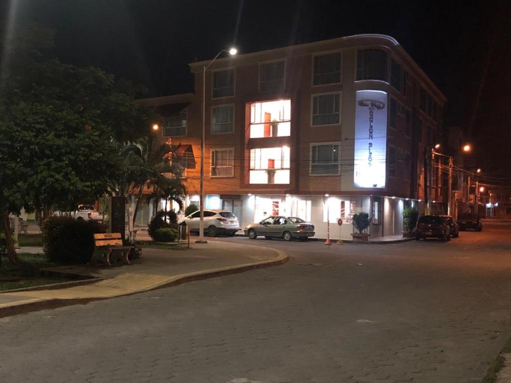 图马科Colon Plaza Hotel的一座夜间建筑,前面有车停放