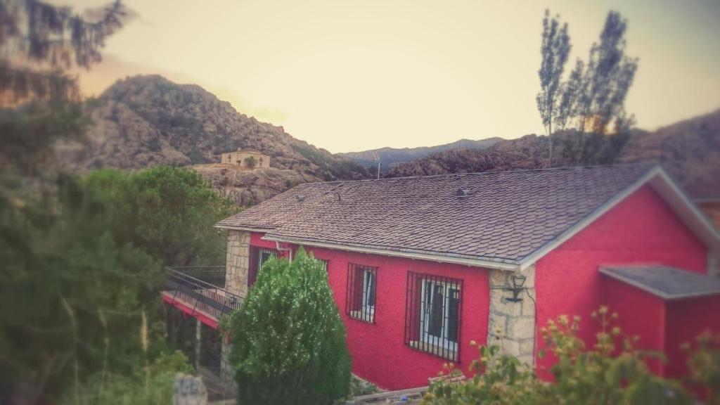 曼萨纳雷斯-埃尔雷亚尔Casa Piedra Libre的一座红色的房子,后面有山