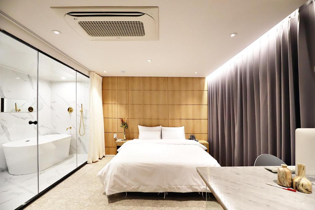 光州Biennale Hotel的卧室配有1张床、浴缸和水槽。