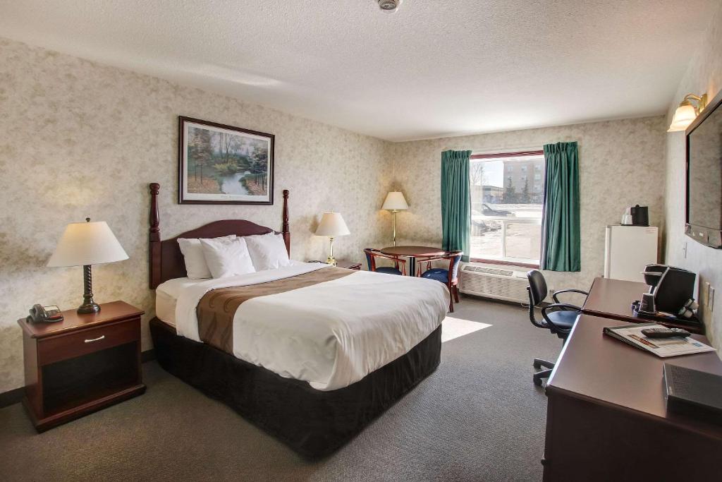 尼斯库Ramada by Wyndham Nisku Edmonton Airport的配有一张床和一张书桌的酒店客房