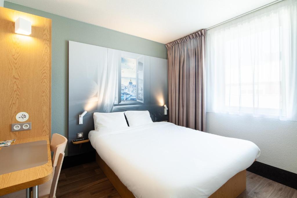 勒布尔热B&B HOTEL Paris Le Bourget的一间设有大床和窗户的酒店客房