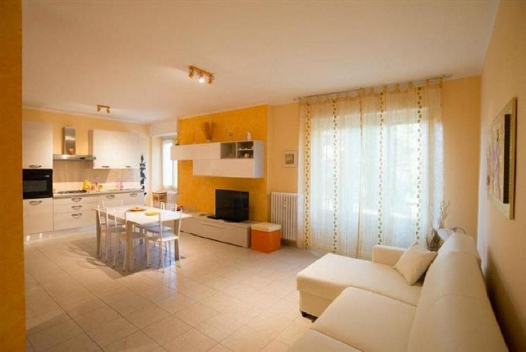 萨尼科Vittorio Veneto Apartments的一间带白色沙发的客厅和一间厨房